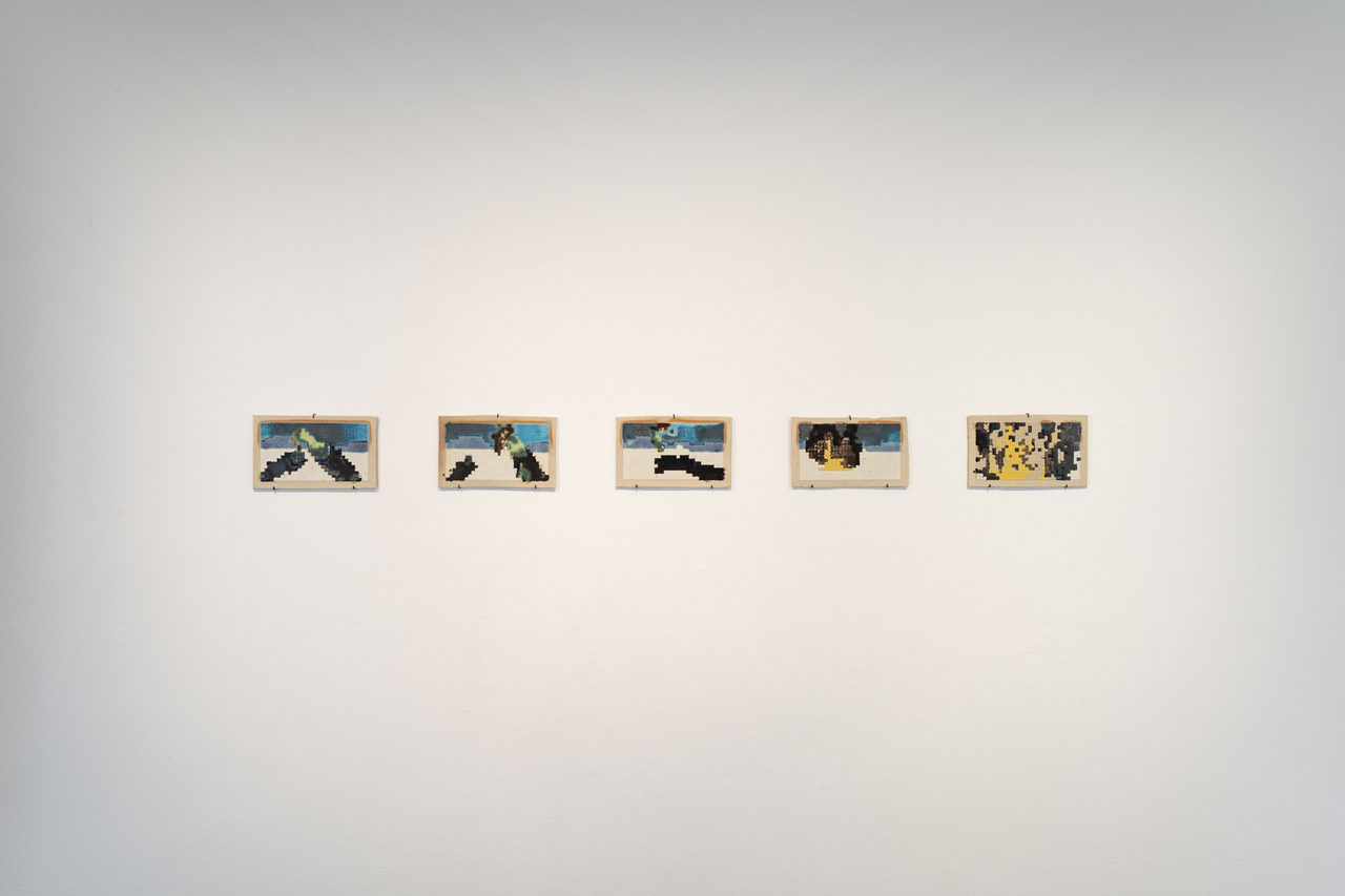 Five small ceramic panels in pale wooden frames hang evenly spaced on a white wall; each carries a coarse, pixel-like image in blue, green, black and yellow, together reading as a sequence of frames.